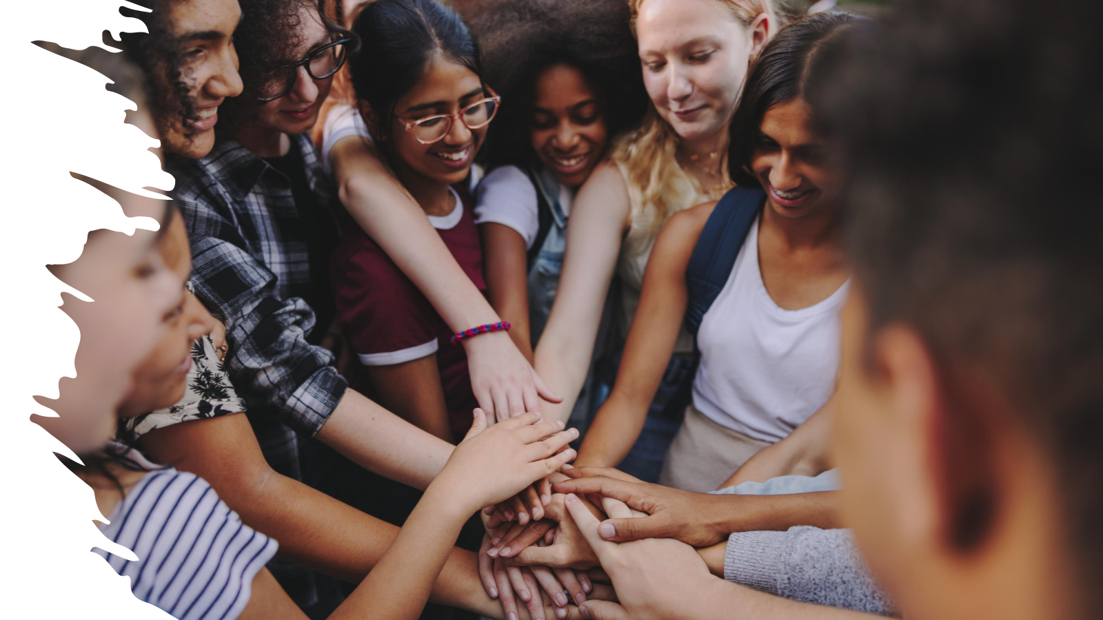 Several young people crossing hands on top of each other 